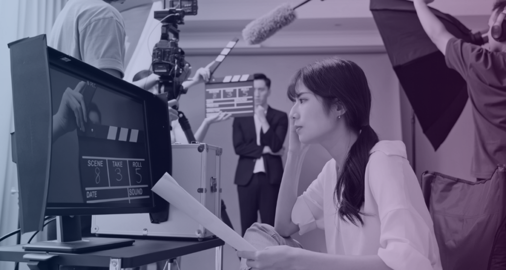 A female director watches behind the camera as a scene unfolds, taking advantage of diversity bonuses in a film production incentive.  